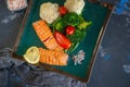 Diet serving of salmon with lemon, broccoli and vegetables. Two pieces of grilled salmon are served on a beautiful plate Royalty Free Stock Photo