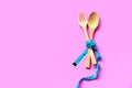 Diet slimming. Blue Measuring tape wrapped around wood fork lying on colorful pink background.