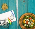 bicycle model, salad of fresh vegetables, notepad, stopwatch and tape measure on a blue wooden table Royalty Free Stock Photo