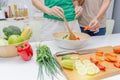 Diet. two young pretty woman in green shirt standing and preparing the vegetables salad in bowl for good healthy in modern kitchen Royalty Free Stock Photo