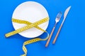 Diet for weight loss concept. Proper nutrition. Medical starvation. Empty plate with fork and knife near measuring tape