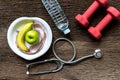 Diet and weight loss for healthy care with medical stethoscope, fitness equipment,measuring tap,fresh water and green apple on woo Royalty Free Stock Photo