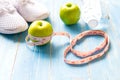 Diet and weight loss with measuring tap, green apple, water and sneakers for fitness on blue wooden background top view Royalty Free Stock Photo