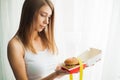 Diet. Woman with guilty feeling to eat a hamburger