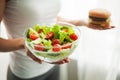 Diet. Woman Measuring Body Weight On Weighing Scale Holding Burger and Salat. Sweets Are Unhealthy Junk Food. Dieting Royalty Free Stock Photo