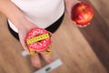 Diet. Woman Measuring Body Weight On Weighing Scale Holding Donut and apple. Sweets Are Unhealthy Junk Food. Dieting, Healthy Eati Royalty Free Stock Photo