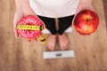 Diet. Woman Measuring Body Weight On Weighing Scale Holding Donut and apple. Sweets Are Unhealthy Junk Food. Dieting, Healthy Eati Royalty Free Stock Photo