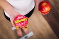 Diet. Woman Measuring Body Weight On Weighing Scale Holding Donut and apple. Sweets Are Unhealthy Junk Food. Dieting, Healthy Eat Royalty Free Stock Photo