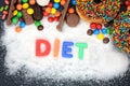 Diet word written on white sugar powder with various sweets