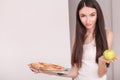Diet. Young beautiful woman makes a choice between healthy lifestyle and harmful food. The concept of healthy eating and obesity. Royalty Free Stock Photo