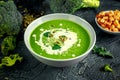 Dietary Broccoli smooth cream soup with sprinkle of sunflower seeds, parsley leaves and croutons on stone table. Royalty Free Stock Photo