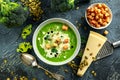 Dietary Broccoli smooth cream soup with sprinkle of sunflower seeds, parsley leaves and croutons on stone table.