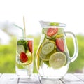 Dietary detox drink with yellow lemon juice, red strawberry, green cucumber and mint leaves in clear water with ice on the wooden Royalty Free Stock Photo