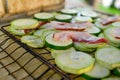 Dietary green zucchini with slices of juicy bacon frying on a grill over a fire. S