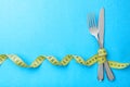 Dietary recipe dishes for breakfast. Fork and knife are wrapped in yellow measuring tape on blue background
