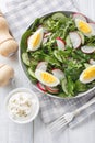 Dietary salad with radish, cucumber, lettuce mix, spinach and eggs close-up in a plate. Vertical top view