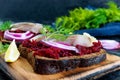 Dietary sandwiches with beets, slices of salted herring and red onion on rye bread on a black background Royalty Free Stock Photo