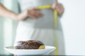 Dietary for slim shape concept. Donut on the table have a woman measuring her waist