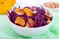 Dietary spicy salad of red cabbage, tangerine and raw peanuts in a ceramic bowl