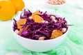 Dietary spicy salad of red cabbage, tangerine and raw peanuts in a ceramic bowl