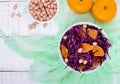 Dietary spicy salad of red cabbage, tangerine and raw peanuts in a ceramic bowl on a white wooden background.