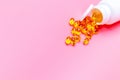 Dietary supplement gel capsules. pills spilling out of prescription bottle on pink background. Royalty Free Stock Photo