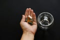 Dietary supplements. Hand holding omega 3, spirulina, chlorophyll,magnesium  capsules above glass of water. Morning dose of pills Royalty Free Stock Photo