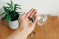 Dietary supplements. Hand holding spirulina capsules above glass of water on wooden table. Morning vitamin nutrient pill. Health