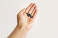 Dietary supplements. Hand holding spirulina capsules on white wall background. Morning vitamin nutrient pill. Health support and