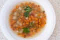 Dietary vegetable soup with carrots, green peas, onions, parsley in a white plate. Vegetarian menu. Healthy eating Dietary food.