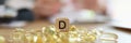 Dietician doctor and pile of vitamin D capsules with D symbol on wooden cube.
