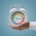 Dietician holding a clock with vitamins