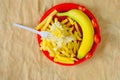 Dieting concept: Plastic plate with greasy french fries and a fresh banana and tomatos. Getting slim and fit for the springtime Royalty Free Stock Photo