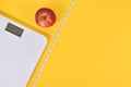 Dieting concept with scale, measuring tape and apple on yellow background Royalty Free Stock Photo