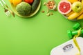 Dieting concept. Top view photo of plates with fruits vegetables nuts cutlery tape measure scales and dumbbells on isolated green Royalty Free Stock Photo