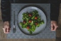 Top view of woman hands and big grey plate with green leaves of salad. Royalty Free Stock Photo