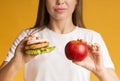 Burger And Apple In Hands Of Unrecognizable Woman, Closeup