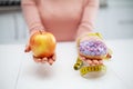 Dieting concept. Young Woman choosing between Fruits and Sweets Royalty Free Stock Photo