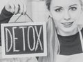 Happy woman holding board with detox sign