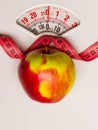 Apple with measuring tape on weight scale. Dieting Royalty Free Stock Photo