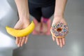 Dieting, healthy eating. Woman measuring body weight on weight scale at home She holds donuts and bananas in top view Royalty Free Stock Photo