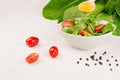 Dieting raw healthy food - fresh green salad with tomatoes, pepper and olive oil on soft white wood board, closeup, copy space. Royalty Free Stock Photo