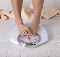 Dieting woman`s feet covering up scale reading Royalty Free Stock Photo