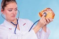 Dietitian examine sweet roll bun with stethoscope.