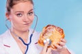 Dietitian examine sweet roll bun with stethoscope.