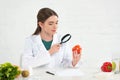 Dietitian in white coat looking at tomato