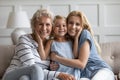 Different age and generation relatives beautiful women hugging posing indoors