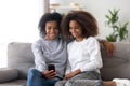 Different ages females sitting on couch at home using smartphone Royalty Free Stock Photo