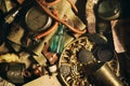 Different antique items on the table: bronze jewelry, old money, retro manometer, magnifier, glass bottle, silverware. Vintage