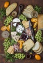 Different appetizers on the board: cheese, prosciutto, ham, bread, olives, grapes Royalty Free Stock Photo